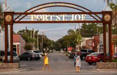 two people crossing the street in front of a sign that says port st joe on it