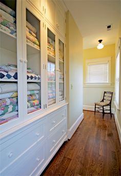 a room filled with lots of white furniture next to a wall covered in cloths