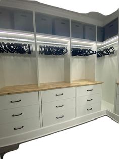 an empty walk in closet with white cabinets and drawers