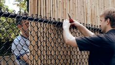 a man holding a pair of scissors next to a fence