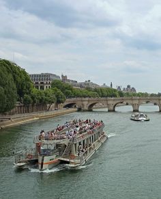 a boat filled with people traveling down a river next to a bridge and stone bridges