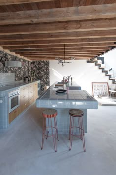 a kitchen with two stools next to an island in the middle of the room