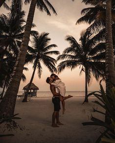 a couple kissing on the beach under palm trees