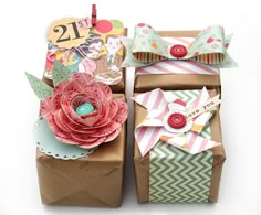 two boxes with paper flowers on them and some tags attached to the top of each box