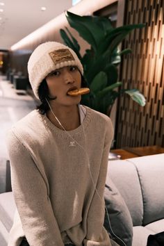 a woman sitting on a couch while wearing headphones and eating something in her mouth