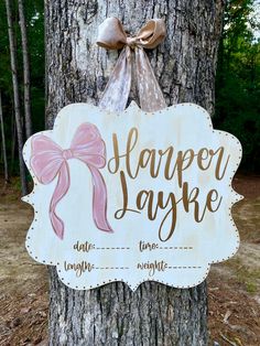 a wooden sign that says happy yayake with a pink bow hanging from the side of a tree