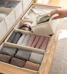 an open drawer with folded towels and socks in it, being held by someone's hand