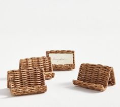 three wicker coasters sitting next to each other on a white surface with a place card holder in the middle