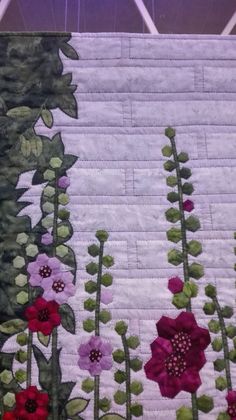 a quilted wall hanging with flowers on it