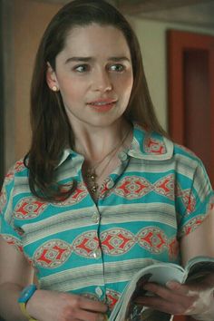 a woman in a blue and white shirt holding a book