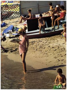 a woman in a pink bathing suit walking on the beach with her son and daughter