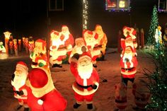 christmas decorations are displayed in front of a house with santas on the lawn and trees