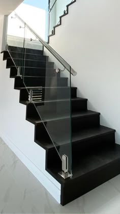 an image of a stair case with glass handrails and black treading on the bottom