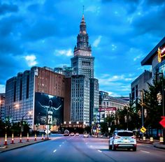 a city street with tall buildings and cars driving down the road at dusk or dawn