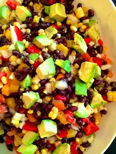 a white bowl filled with black beans, avocado and corn salad on top of a table