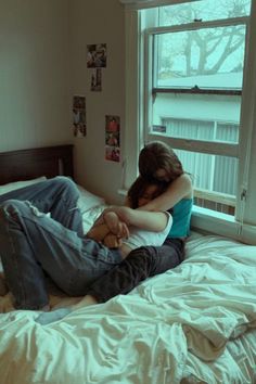 a man and woman laying in bed with their arms around each other's shoulders