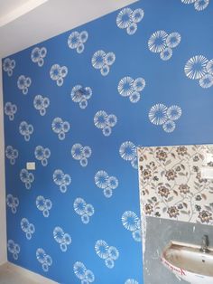 a bathroom with blue wallpaper and a sink in the foreground is being painted