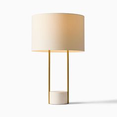 a table lamp with a white shade on the base and a gold frame around it