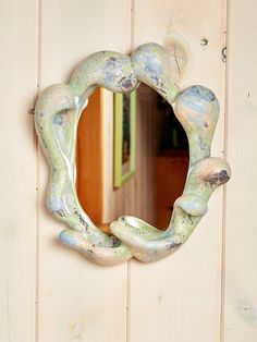 a mirror hanging on the side of a wooden wall next to a door with peeling paint