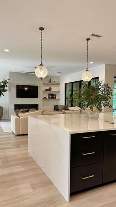 a large kitchen with an island in the middle and two lights hanging from the ceiling