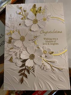 a white and gold card with flowers on it