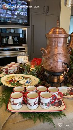 a table topped with cups and plates covered in christmas decorations next to a potted plant