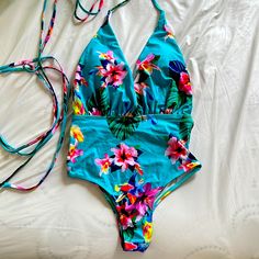 Nwot Tropical Floral One Piece Swimsuit. Size Small. Never Worn, Only Tried On. Moderate Coverage Bottom, Plunge Top, Tie Around. Has Padding. Green Floral Print Bodysuit For Beach, Green Floral Print Summer Bodysuit, Tropical Spring Bodysuit For Poolside, Tropical Spring Bodysuit For Pool, Tropical Spring Pool Bodysuit, Tropical Spring Bodysuit For Vacation, Blue Tropical Bodysuit For Beach, Blue Tropical Bodysuit For The Beach, Blue Triangle Top Bodysuit For Vacation