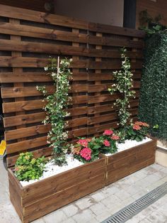 a wooden planter filled with flowers next to a wall made out of pallets