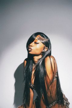 a woman with long black hair sitting on the floor wearing a bathing suit and chain around her neck