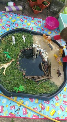 a young child playing with toys in a play pond on a blanket covered picnic table