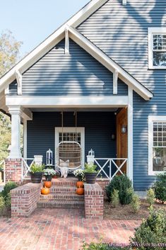 a blue house with pumpkins on the front porch