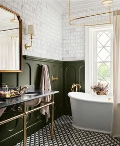 a bathroom with green walls, black and white tile flooring and a gold framed mirror on the wall