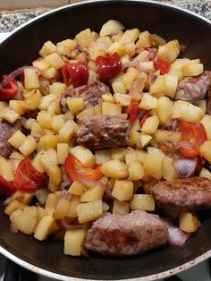 a skillet filled with meat and vegetables on top of a stove burner oven