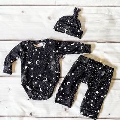 two pieces of black and white baby clothes with stars, moon and clouds on them