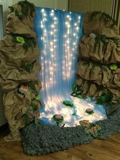 a waterfall made out of paper and rocks with lights in the water on it's sides