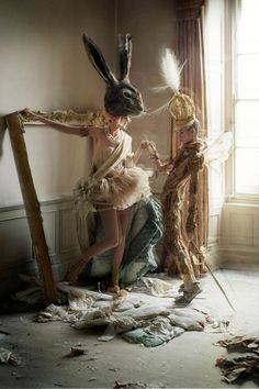 two women dressed in costumes and hats standing next to each other near a mirror with feathers on it