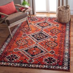 an orange rug with black and white designs on it in front of a chair next to a window