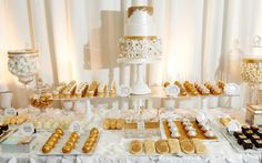 a table topped with lots of different types of desserts and pastries next to a white curtain