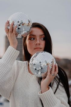 a woman holding two disco balls in front of her face