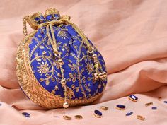 Blue Potli Bag with Pearl Handle Strap With its classy zari work and a pearl handle strap all in gold this Blue Potli Bag is ideal for this wedding season. Fabric Raw Silk Color Royal Blue Embroidery Zari Work in Gold Size amp Dimensions Height - 8 inWidth - 7.5 inDepth - 1.5 in Strap Pearl Handle Strap Closure Tasseled Drawstring Compartments Single compartment Care Wipe with a soft clean amp dry cloth to remove dust When not in use store it in a dust bag for longer product life Avoid liquid ex Elegant Festive Openable Potli Bag, Gold Openable Potli Bag For Wedding, Elegant Festival Potli Bag, Festive Party Potli Bag With Openable Detail, Festive Openable Potli Bag For Parties, Festive Traditional Potli Bag, Traditional Gold Pouch For Festive Season, Gold Pouch With Latkans For Festivals, Traditional Gold Bags With Latkans