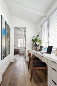 there is a desk with two laptops on it in the room that has white walls