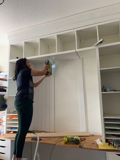 a woman is working on some shelves in the room