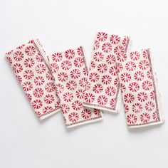 four red and white paper napkins on a white surface with small circles in the middle