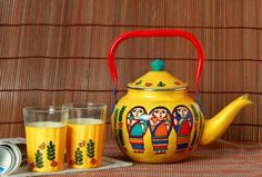 a yellow teapot and two glasses on a table