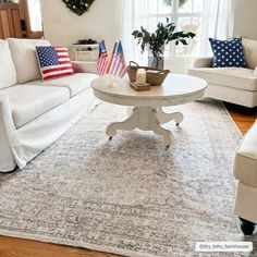 a living room with white furniture and american flags on the rug