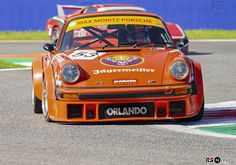 an orange porsche racing car driving on a race track