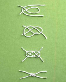 four pieces of white string tied together on a green surface with two pairs of scissors next to each other