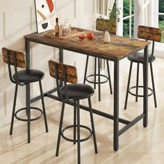 a kitchen table with four stools in front of it and an art piece on the wall