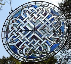 a large stained glass window hanging from the side of a building with trees in the background