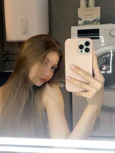 a woman is holding up her phone in front of the washing machine